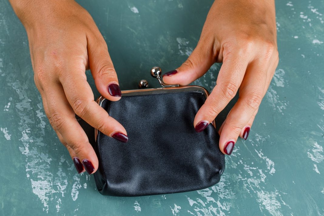 Business and financial concept on plaster background flat lay. woman opening coin purse.