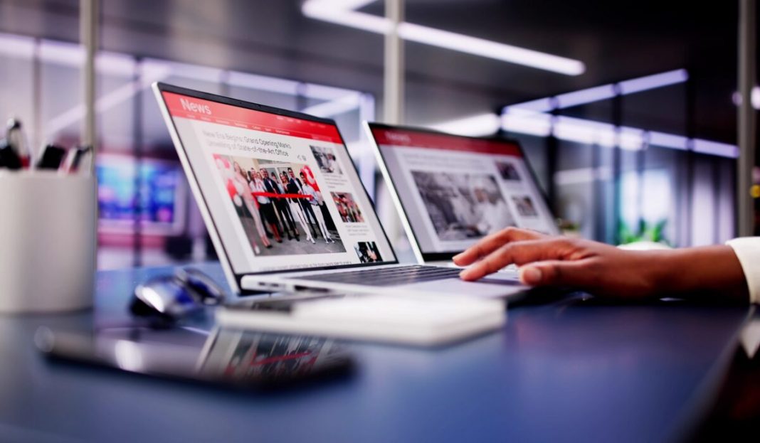 American,Woman,Views,Online,News,Articles,On,Laptop,And,Phone