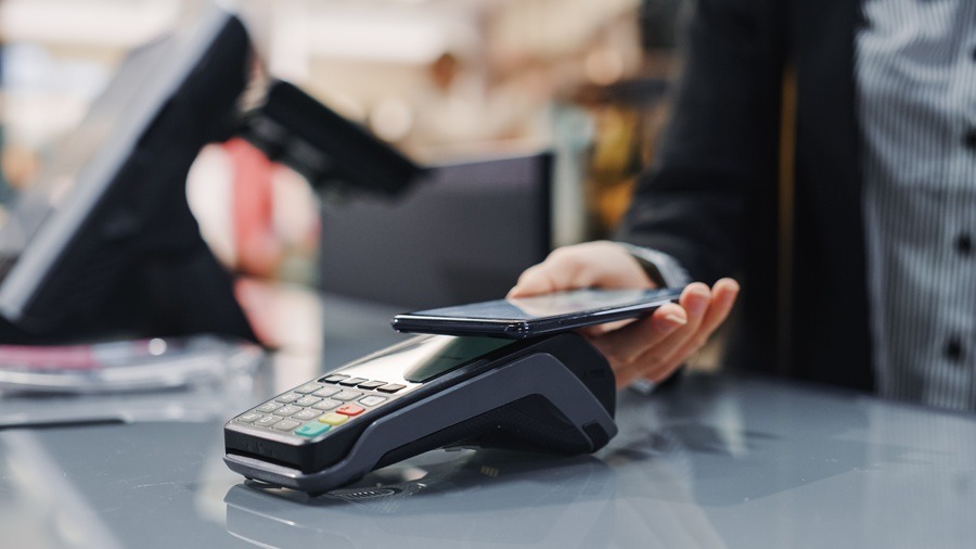 Clothing,Store:,Woman,At,Counter,Buys,Clothes,Paying,With,Smartphone